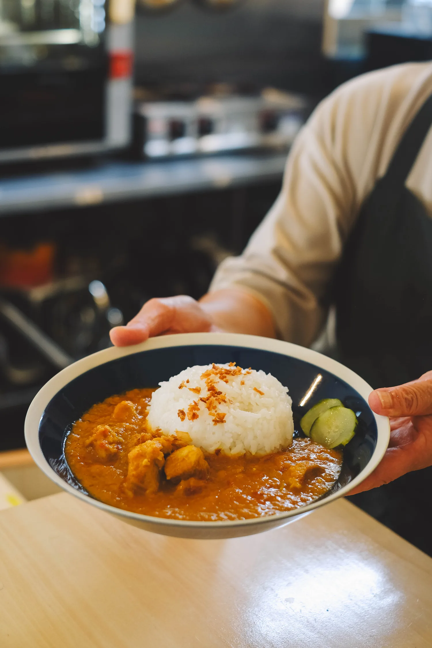 カウンター越しに差し出される、特製スパイスチキンカレー