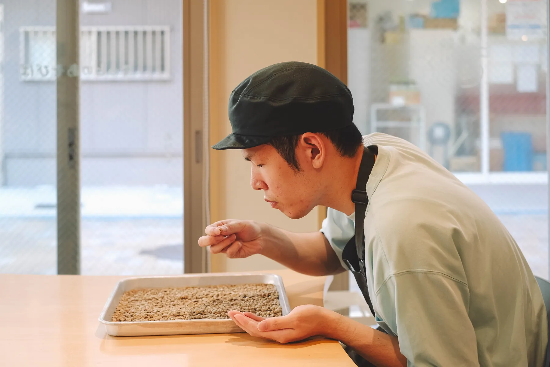 トレイに広げた生豆から欠点豆を一粒ずつ選り分けるスタッフ