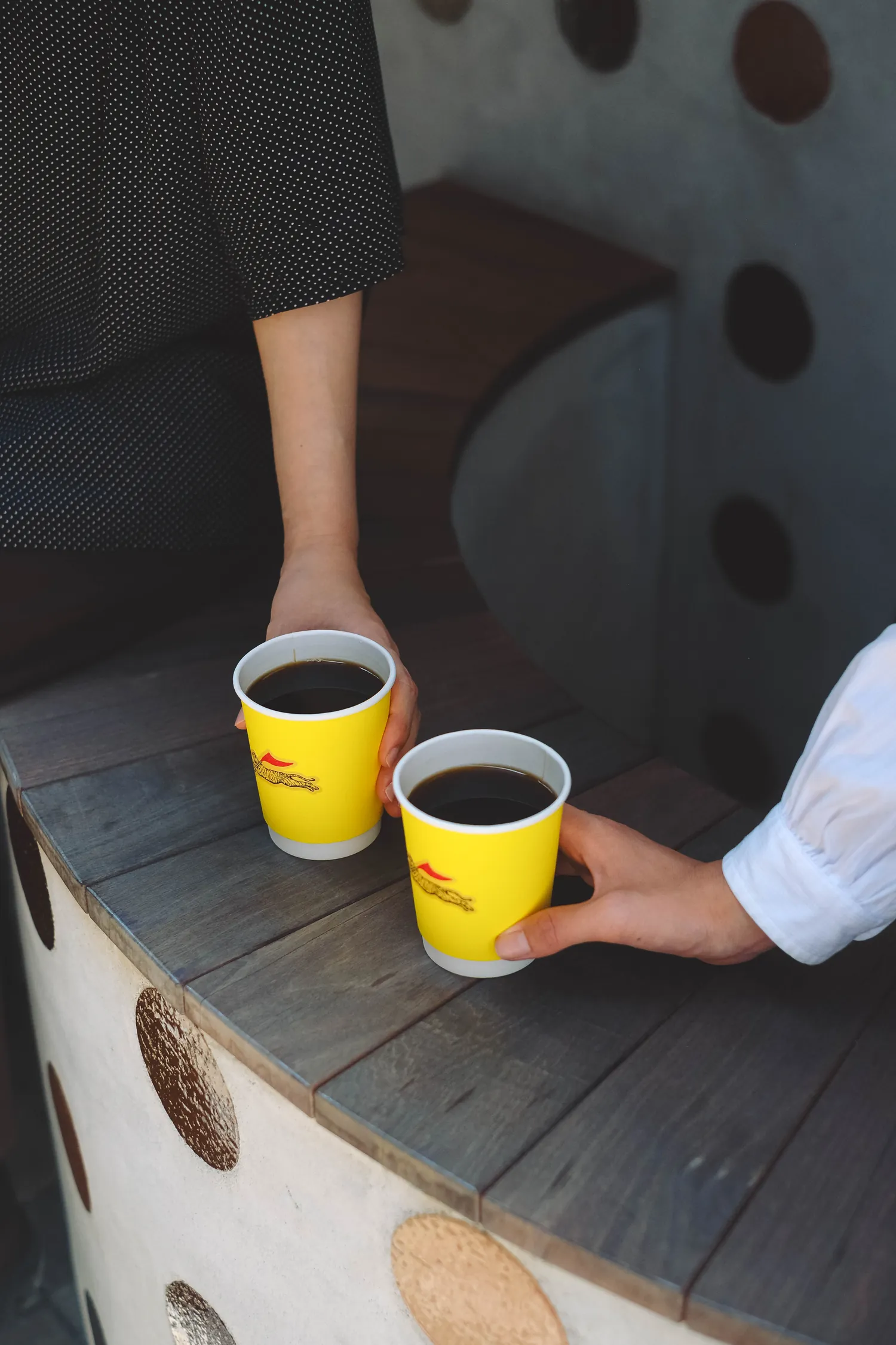 TETTOのイエローのカップに注がれたコーヒーを、ふたりが手に取っている