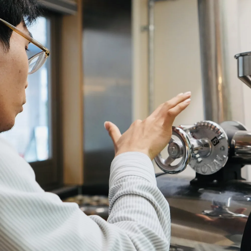焙煎機のダイヤルに手をのばすスタッフ